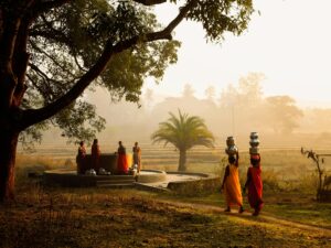 Women bearing water pots walk beside a well in the picturesque Araku Valley, India.
