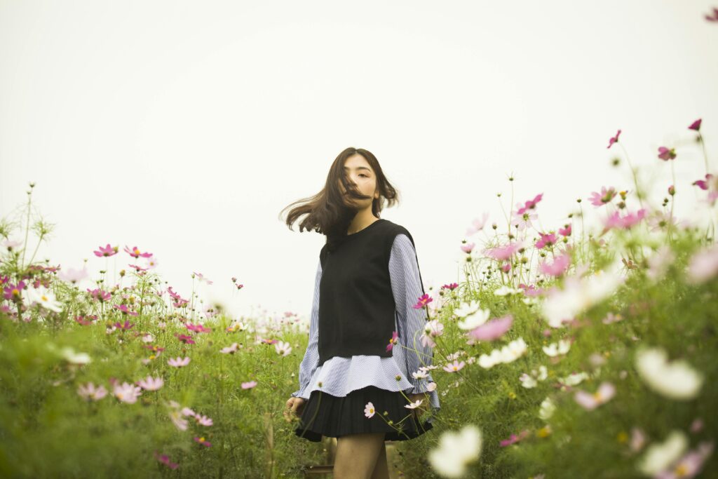 A serene image of a young woman in a vibrant flower field, embracing nature.