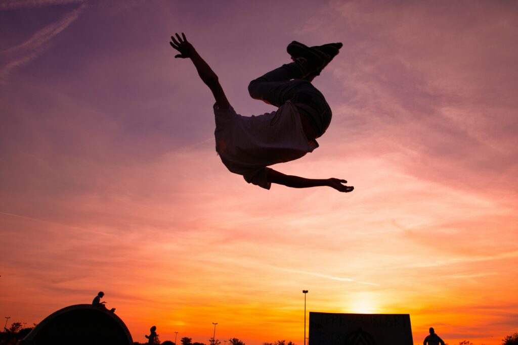 Dynamic silhouette of a man performing a jump against a vibrant sunset in Istanbul.