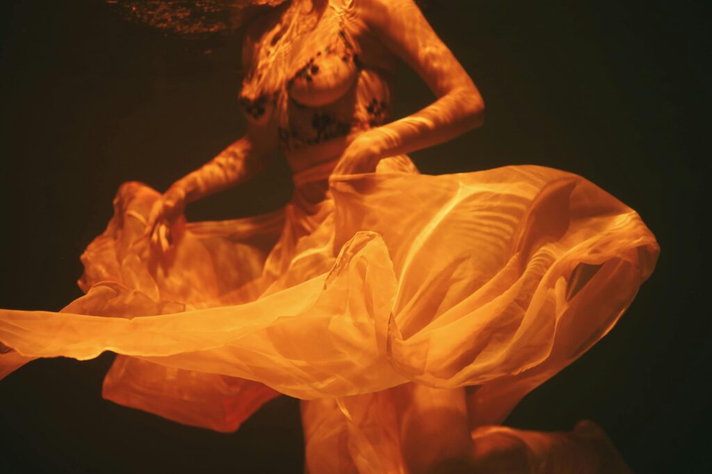Artistic underwater photograph capturing fluidity and grace in swirling fabric.