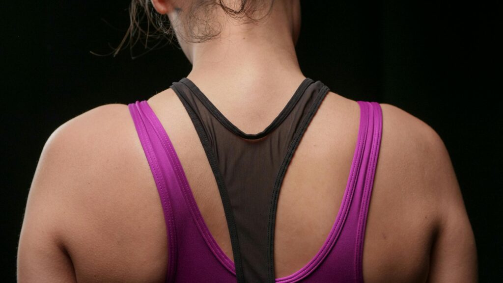 Close-up of a woman in activewear from the back, wearing a purple sports top.
